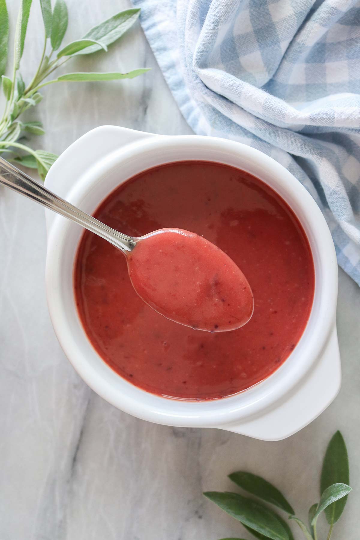 Spoonful of cranberry mustard sauce held above a serving dish of sauce.