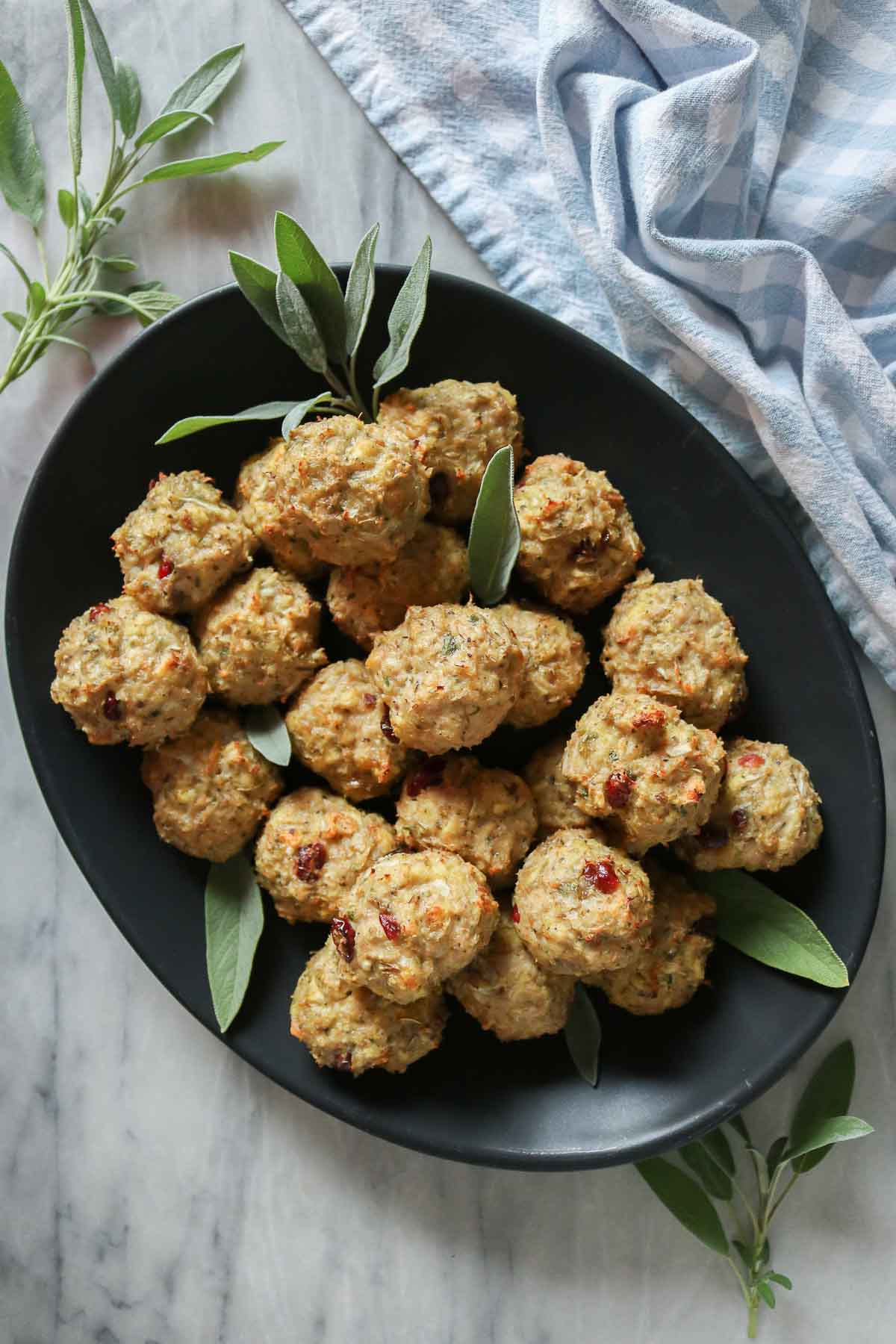 Stuffing chicken meatballs on a black platter.