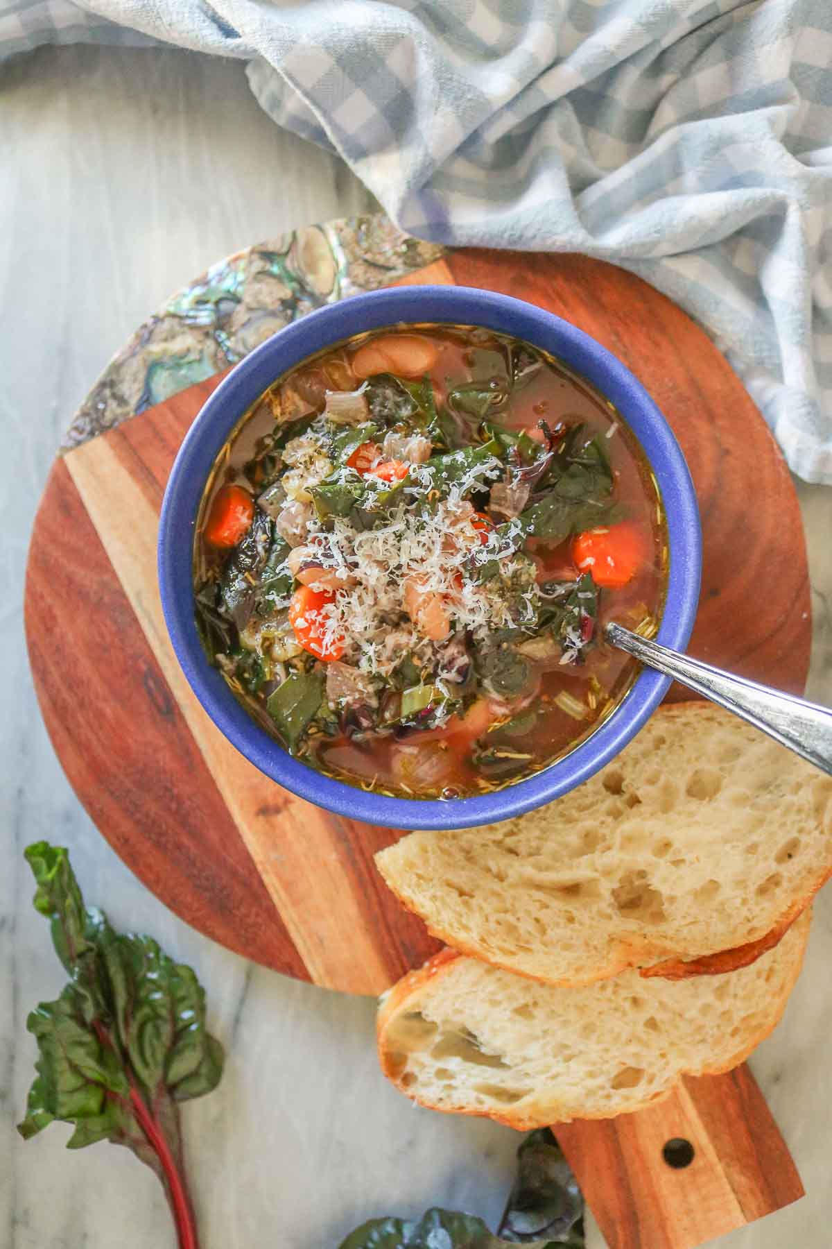 Bowl of bean and Swiss chard soup garnished with grated Parmesan cheese.