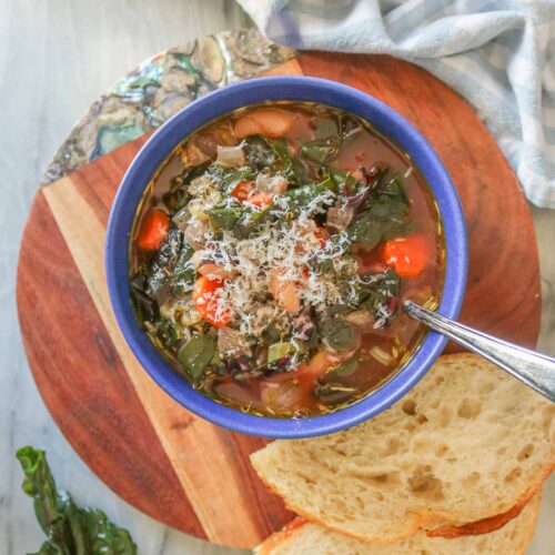 Bowl of bean and Swiss chard soup garnished with grated Parmesan cheese.