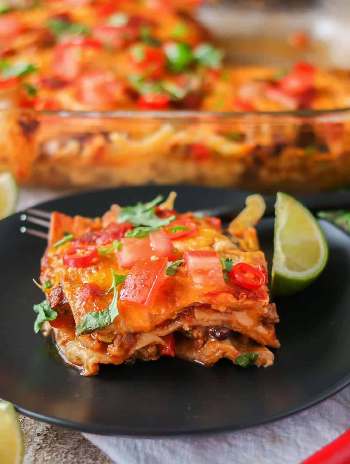 Portion of turkey taco casserole on a plate with a lime wedge.