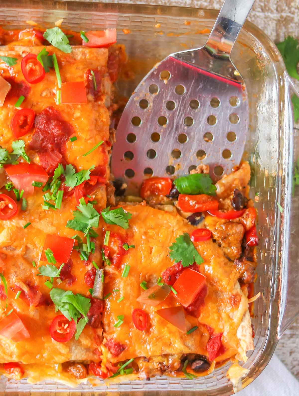 Spatula resting in a turkey taco casserole dish after a piece has been removed.