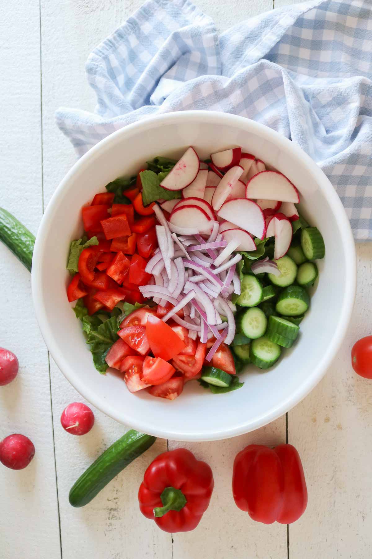 Garden salad ingredients in a bowl before being mixed together.