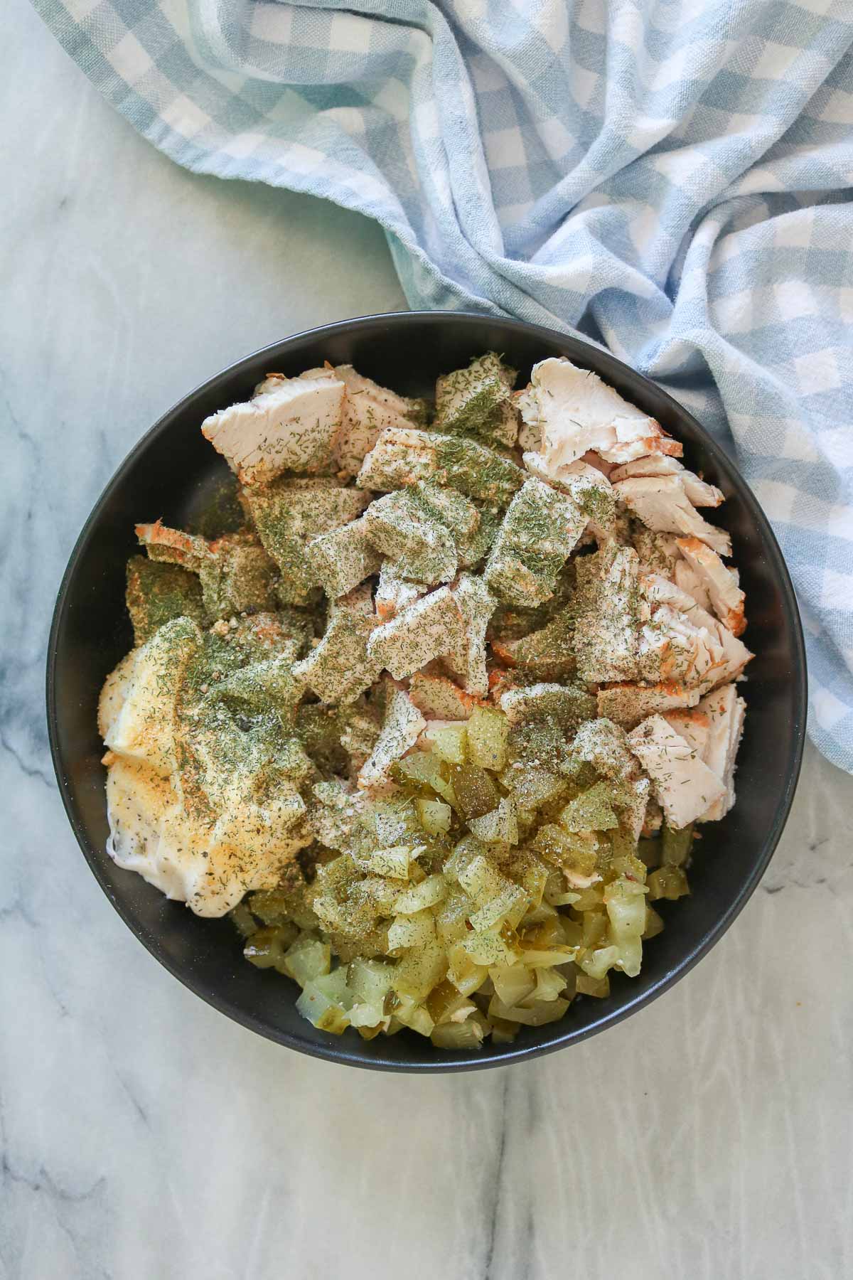 Dill pickle turkey salad ingredients in a bowl before being mixed together.