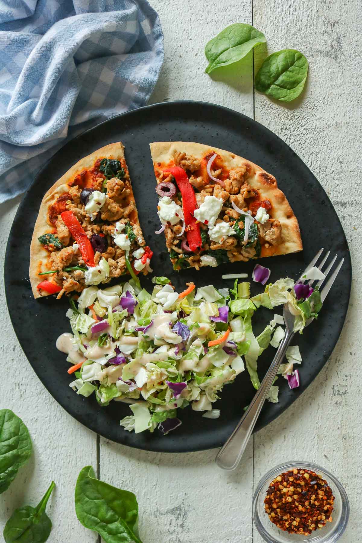 Two slices of pizza and salad on a black plate with a fork.