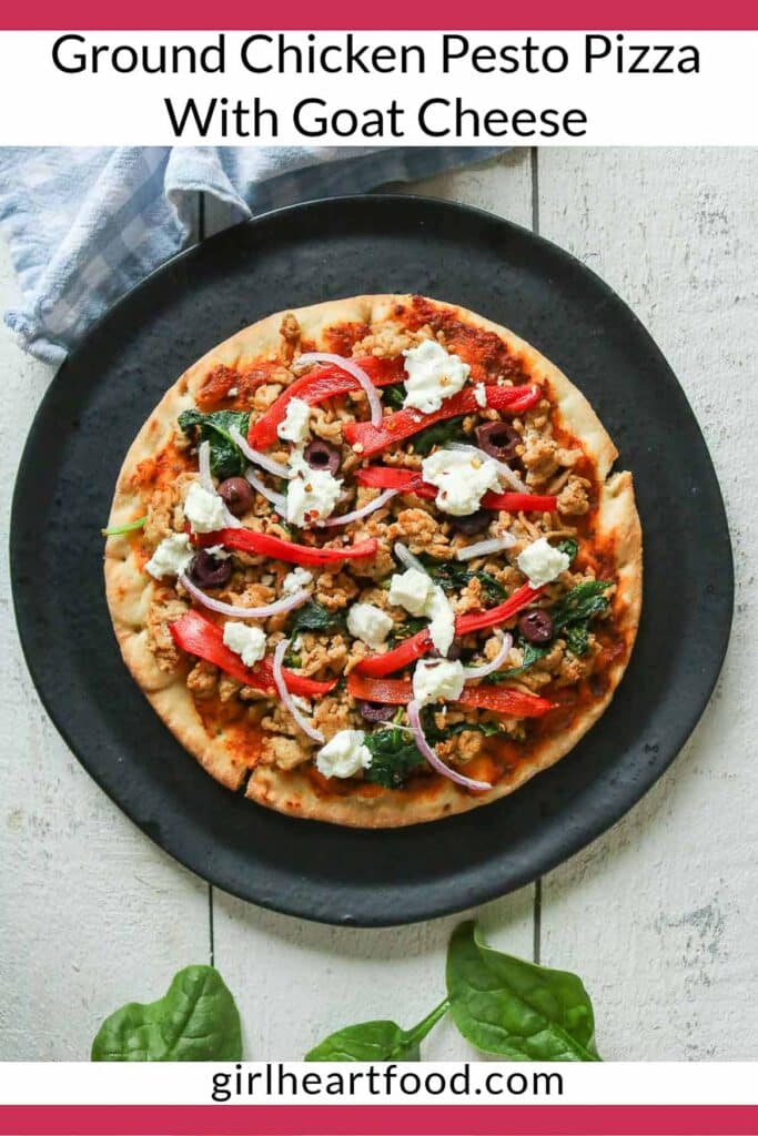 Ground chicken pesto pizza on a black plate before being cut into slices.